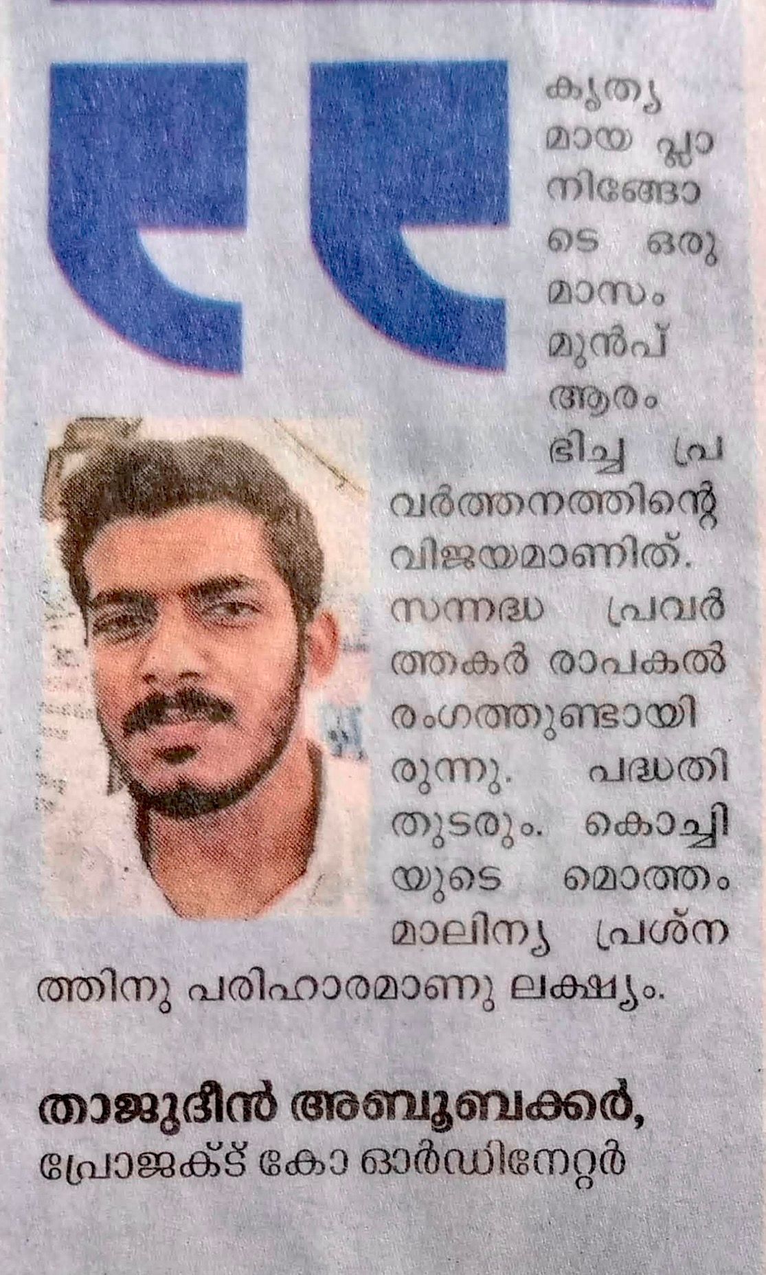 A Malayalam newspaper clipping. A photo of a bearded young man in a white shirt sits beside a printed quote about a project that began a month earlier, saying the work will continue and the aim is a solution to Kochi's waste problem. It is signed with the name Thajudeen Abubakkar, Project Coordinator.